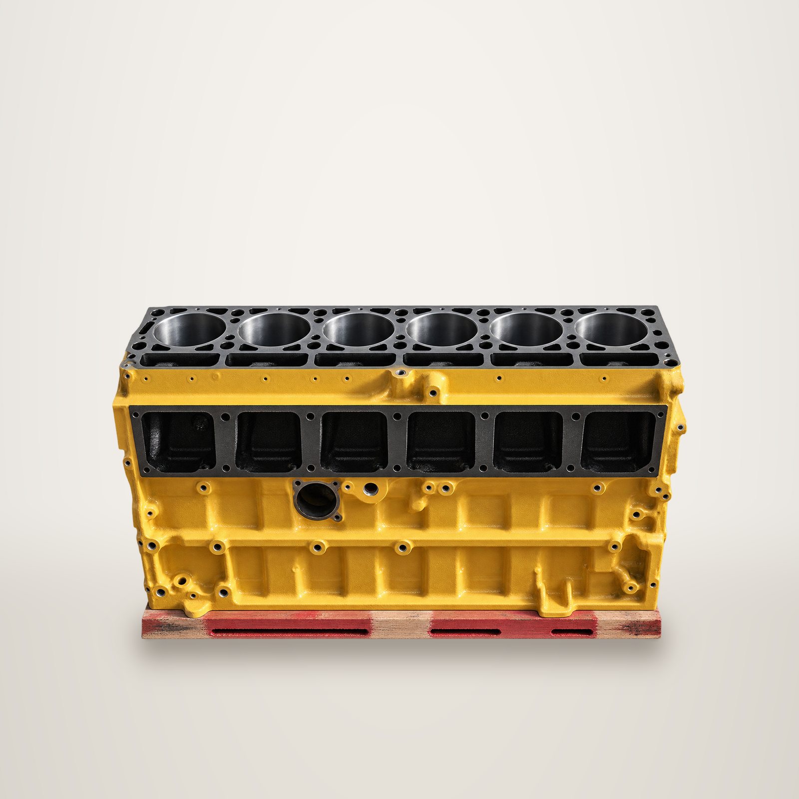 Un bloc moteur industriel jaune à six cylindres, posé sur un support devant un fond clair.